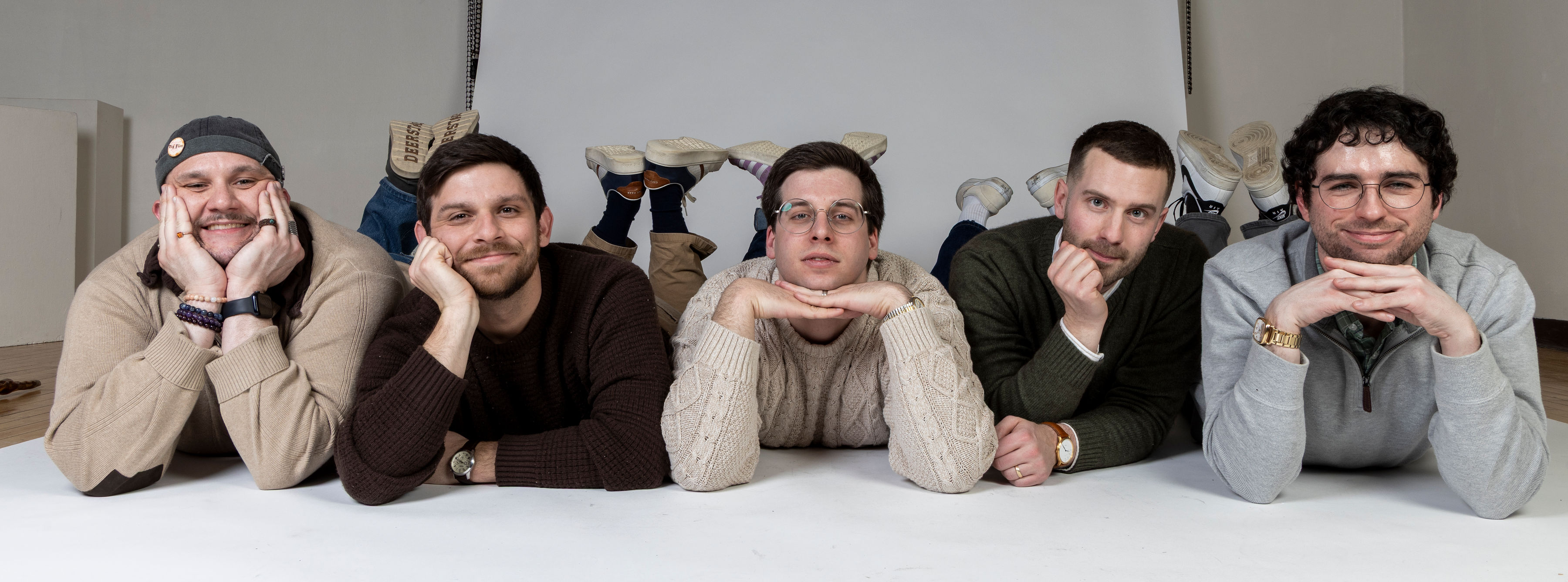 Rapid Fire Improv performers lying shoulder to shoulder and smiling at the camera